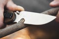 Close-up of the tourist`s hands, sharpening a stick with a knife. The concept of travel, extreme and survival