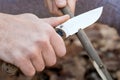 Close-up of the tourist`s hands, sharpening a stick with a knife. The concept of travel, extreme and survival Royalty Free Stock Photo