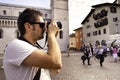 Close-up of a tourist taking a photo, Piazza Duomo, Trento, Italy. In the background the Duomo and people strolling Royalty Free Stock Photo