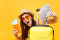 Close up tourist woman in summer casual clothes, hat at suitcase passport cash money on yellow background