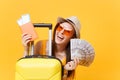 Close up tourist woman in summer casual clothes, hat at suitcase passport cash money on yellow background