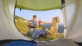 CLOSE UP: Tourists packing their backpacks in front of tent before going home.