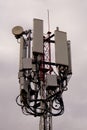 Close-up of tower with 5G and 4G cellular network antenna on grey cloudy sky background