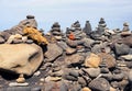 Close up of towers of stacked pebbles and colored stones in a large arrangement on a black sand beach with blue sky Royalty Free Stock Photo