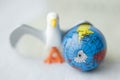 Close up of toy bird next to earth globe against white b