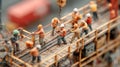 Close-up of toy-like construction workers in orange uniforms using tools with sparks flying on a miniature worksite Royalty Free Stock Photo