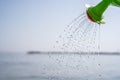 Close Up of a toy watering can pouring a shower of water on the beach. Fun with children on the beach Royalty Free Stock Photo