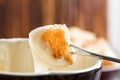 Close up. Traditional french cheese fondue. Crouton dipped into hot cheese fondue on a long-stemmed fork. Winter seasonal meal. Royalty Free Stock Photo