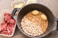 Raw Beef Being Added To A Saucepan Of Potatoes, Onion, Pearl Barley, Beans And Wheat Grains. Royalty Free Stock Photo