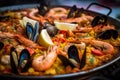 Close-up of a traditional Paella pan with sizzling hot rice, seafood, vegetables and aromatic herbs Royalty Free Stock Photo