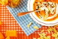 Close-up of pumpkin and carrot soup with cream, parsley, pumpkin seeds and toasted bread on blue and orange tablecloth background Royalty Free Stock Photo