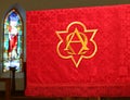 Red church banner in front of blurry stained glass window Royalty Free Stock Photo