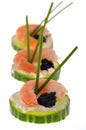 Appetizers with cucumber slices, a shrimp, lump eggs and chives close-up on a white background