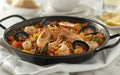 A close-up of a traditional Spanish paella dish filled with shrimp, mussels, and saffron rice. Royalty Free Stock Photo