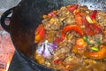 Close up of traditional Uzbek shurpa dish made from lamb and various vegetables at the open fire in cast iron cauldron Royalty Free Stock Photo