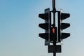 Close-up of a traffic light with a red signal at a crosswalk against a blue sky