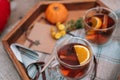 Close up transparent cups with hot spiced tea with star anise, cinnamon stick and a slice of orange on the wooden tray