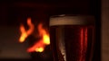 Close-up glass bocal of refreshment cooled beer with foam fireplace in background