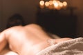 Close-up of a transparent ice cube lying on the lower back of a young girl lying on a couch for spa treatments against