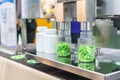 Close up transparent plastic bottle under nozzle dispenser component of automatic medicine capsule bottle filling and counting