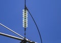 Close up of a transparent turquoise high voltage insulator or isolator in sunlight on electric tower on blue sky background. Royalty Free Stock Photo