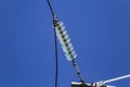 Close up of a transparent turquoise high voltage insulator or isolator in sunlight on electric tower on blue sky background. Royalty Free Stock Photo