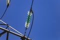 Close up of a transparent turquoise high voltage insulator or isolator in sunlight on electric tower on blue sky background. Royalty Free Stock Photo