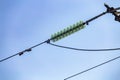 Close up of a transparent turquoise high voltage insulator or isolator in sunlight on electric tower on blue sky background. Royalty Free Stock Photo