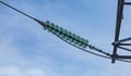 Close up of a transparent turquoise high voltage insulator or isolator in sunlight on electric tower on blue sky background. Royalty Free Stock Photo