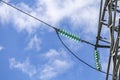 Close up of a transparent turquoise high voltage insulator or isolator in sunlight on electric tower on blue sky background Royalty Free Stock Photo