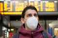 Close-up traveler man wearing KN95 FFP2 face mask at the airport. Young caucasian man with behind timetables board of departures Royalty Free Stock Photo