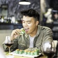 Close-up of trendy Asian man eating yummy sushi with hands at the fusion restaurant - Concept of hungry and social life