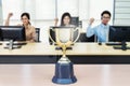 Close up of a trophy in front of a working business people, achieve business concept