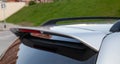 Close-up on the trunk lid of a gray car with a plastic spoiler over the rear window to improve the aerodynamics of the car body