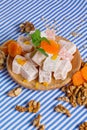 Close-up of turkish delight, dried apricots, bright leaves of mint and walnuts on a striped background, top view.