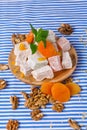 Close-up of turkish delight, dried apricots, bright leaves of mint and walnuts on a striped background, top view.