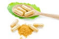 Close up turmeric herbal capsules with green leaf.