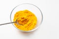 Close-up of turmeric powder in a spoon over a bowl on a white background Royalty Free Stock Photo