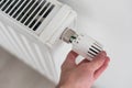 Close-up of turning down the thermostat on a radiator to save energy due to heating cost price hike. Concept of Royalty Free Stock Photo