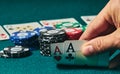 close-up of two aces held in one hand on the green game mat on the right side of the image to leave room for editing, other cards Royalty Free Stock Photo