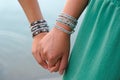 Close up of two holding hands with bracelets on each other Royalty Free Stock Photo