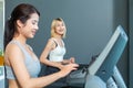 Close up of two beautiful asian girls is wearing workout clothes are working out on the treadmill with smiles face in fitness Royalty Free Stock Photo