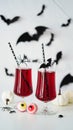 Close-up of two bloody cocktails glass goblets for Halloween,bottle form skull,candy eyes,bats,spiders,pumpkins white background. Royalty Free Stock Photo