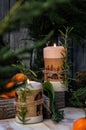 Close up. Two burning Christmas candles, surrounded by tangerines, branches of juniper and rosemary