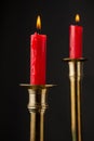 Close-up of two burning red candles in golden candlestick, with selective focus, black background, Royalty Free Stock Photo