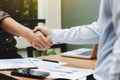 Close-up of two business executives shaking hands with data documents on the table Royalty Free Stock Photo