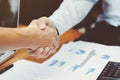 Close-up of two business executives shaking hands with data documents on the table Royalty Free Stock Photo
