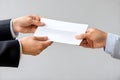 Close-up of two business people exchanging a white envelope in a professional setting. Close-up Royalty Free Stock Photo