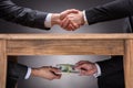 Businesspeople Shaking Hands And Taking Bribe Under Table Royalty Free Stock Photo