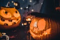 Close up Two Carved luminous pumpkins with scary evil faces, burning candles and paper silhouettes of bats, castle, ghosts on Royalty Free Stock Photo